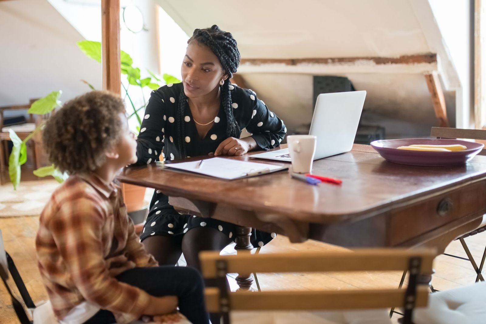 Mãe conversando com o filho à mesa, com um caderno aberto