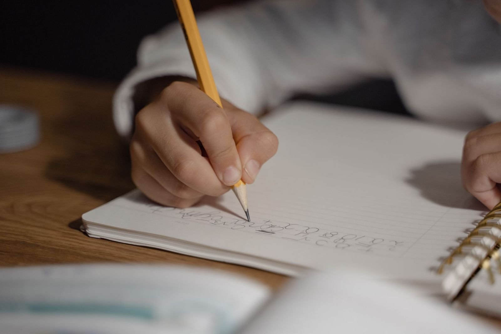 Mão de criança escrevendo a lápis em um caderno